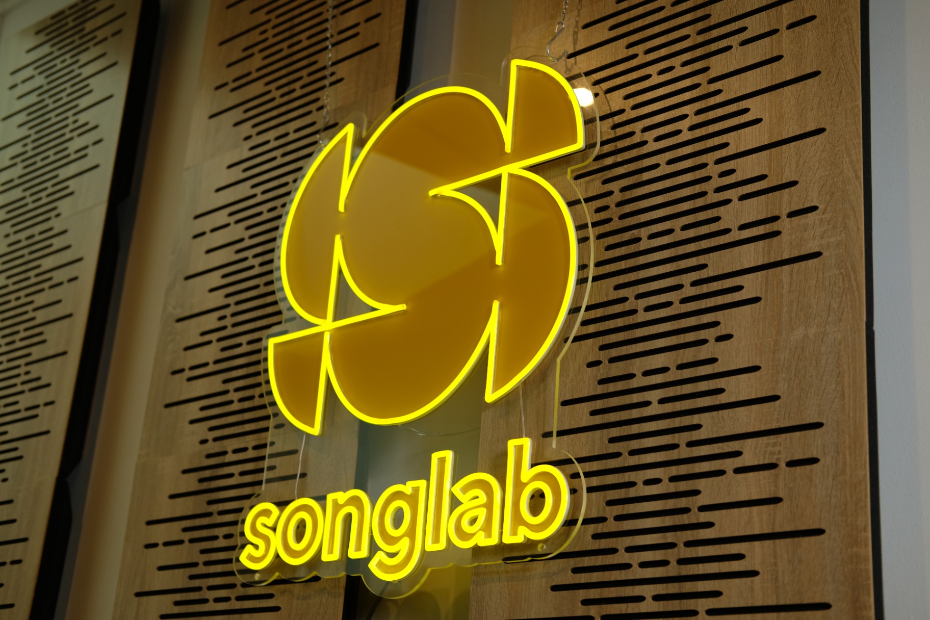 Verlicht Songlab neonlogo op akoestisch houten wandpaneel